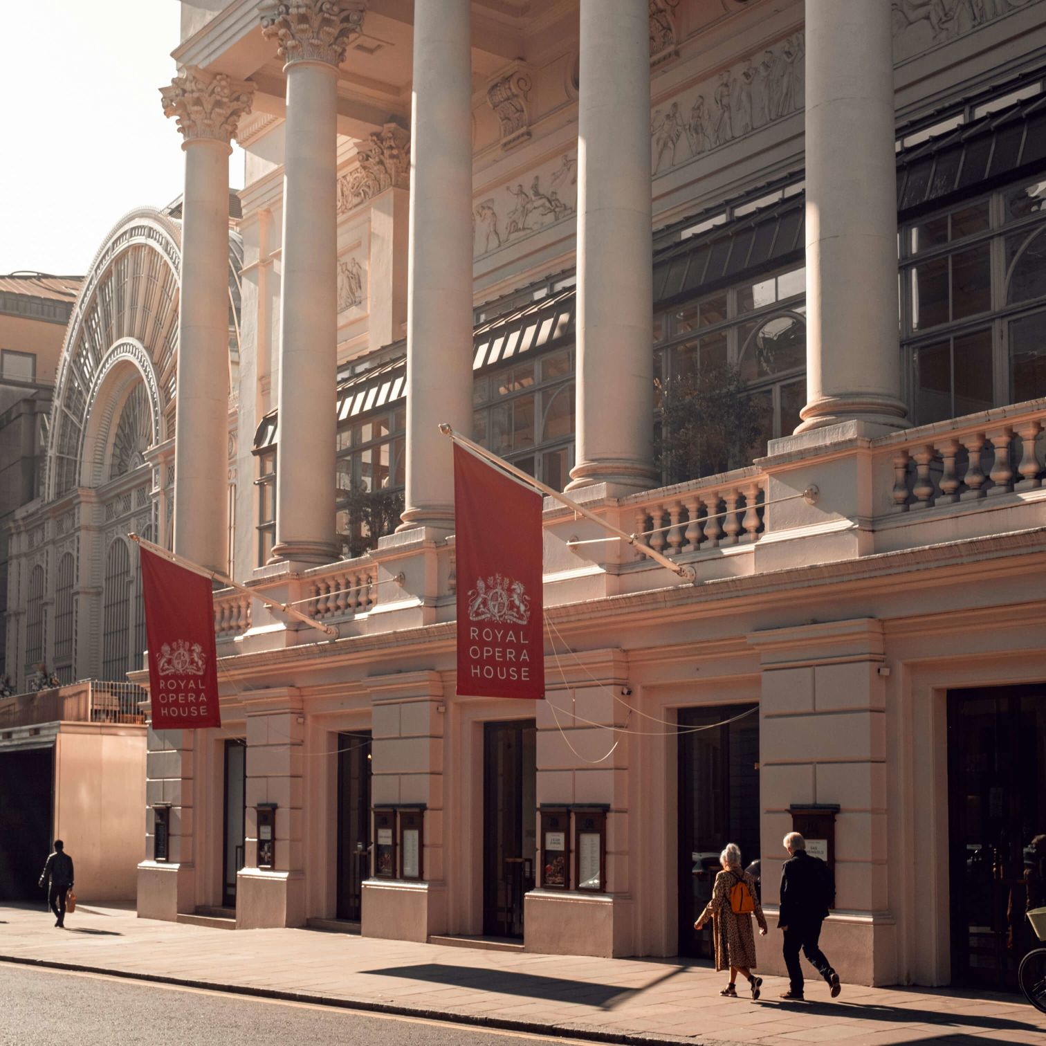 A Building With Pillars And People Walking