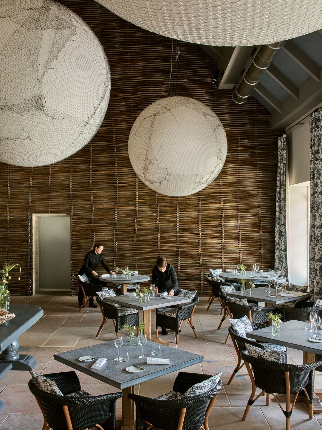 A Couple Of People Sitting At A Table With A Large Chandelier Above Them