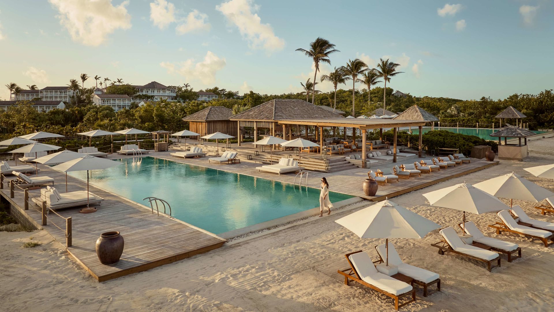 A Pool With Lounge Chairs And Umbrellas Next To It