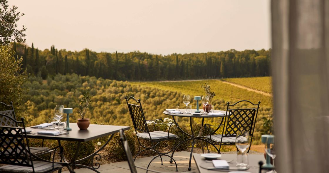 A Table With Chairs And Glasses On It By A Field