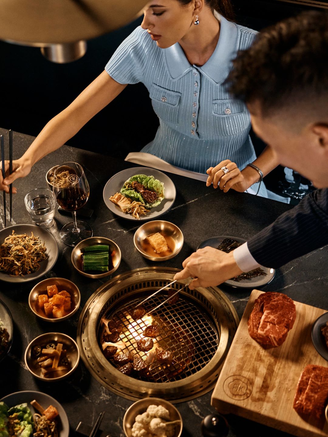 A Woman And A Man Eating At A Table Full Of Food