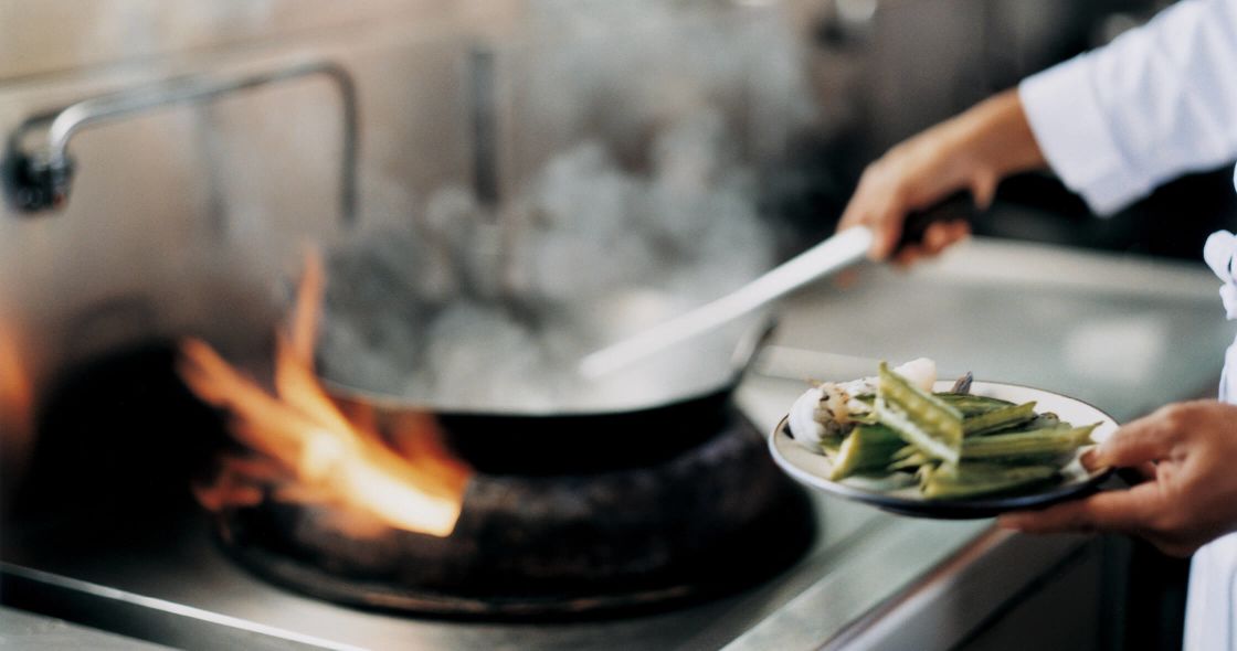 A Person Cooking Food In A Pan