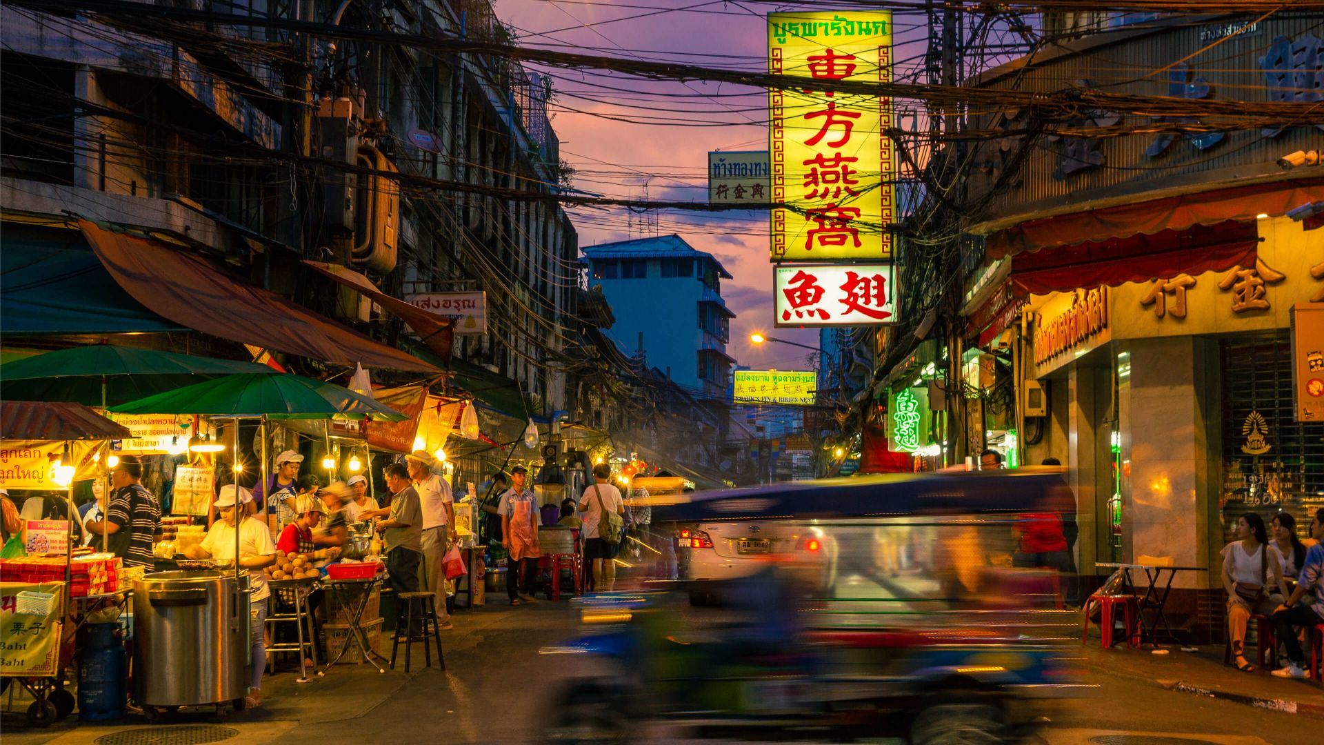 A Busy Street With People And Shops