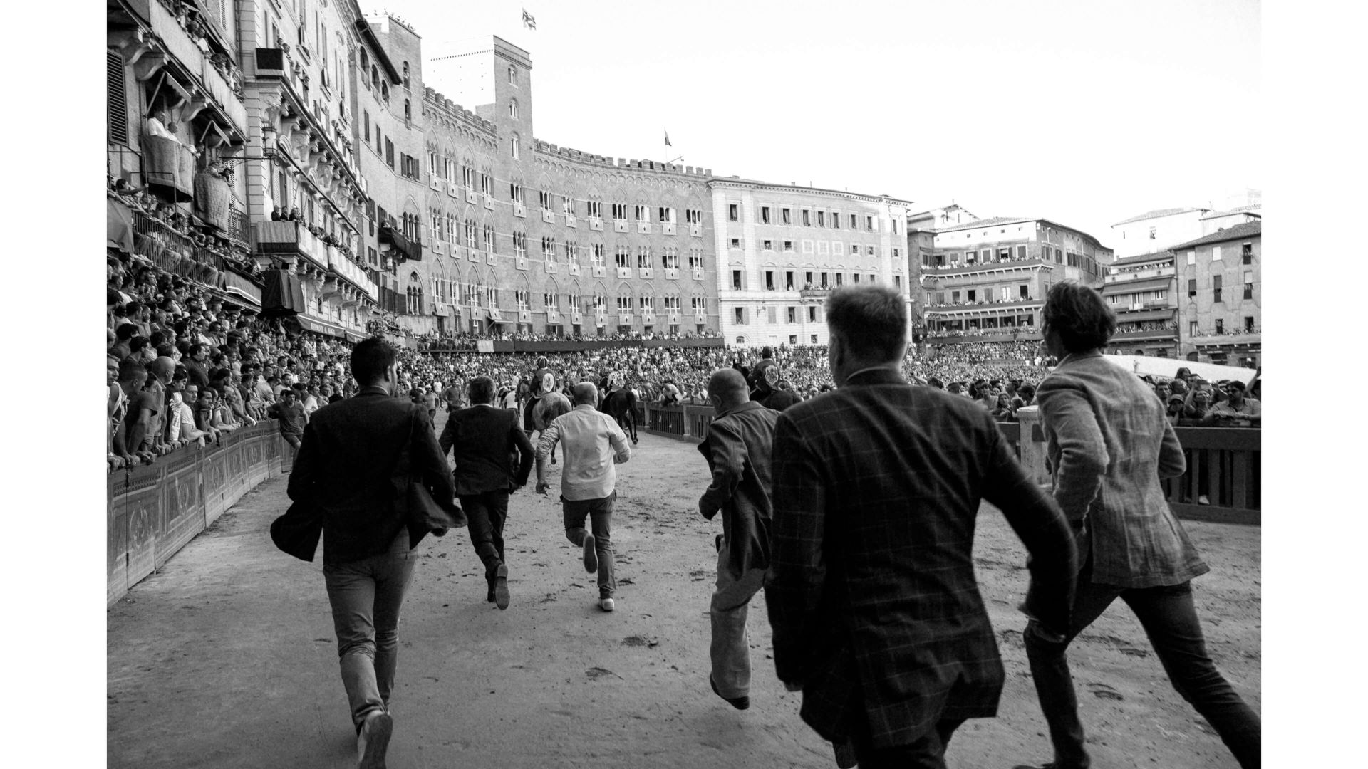 A Group Of People Walking On A Street With Buildings On Either Side
