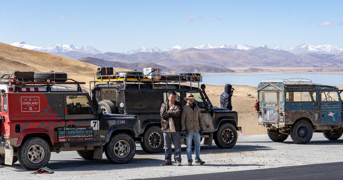 A Group Of Men Standing Next To A Row Of Trucks