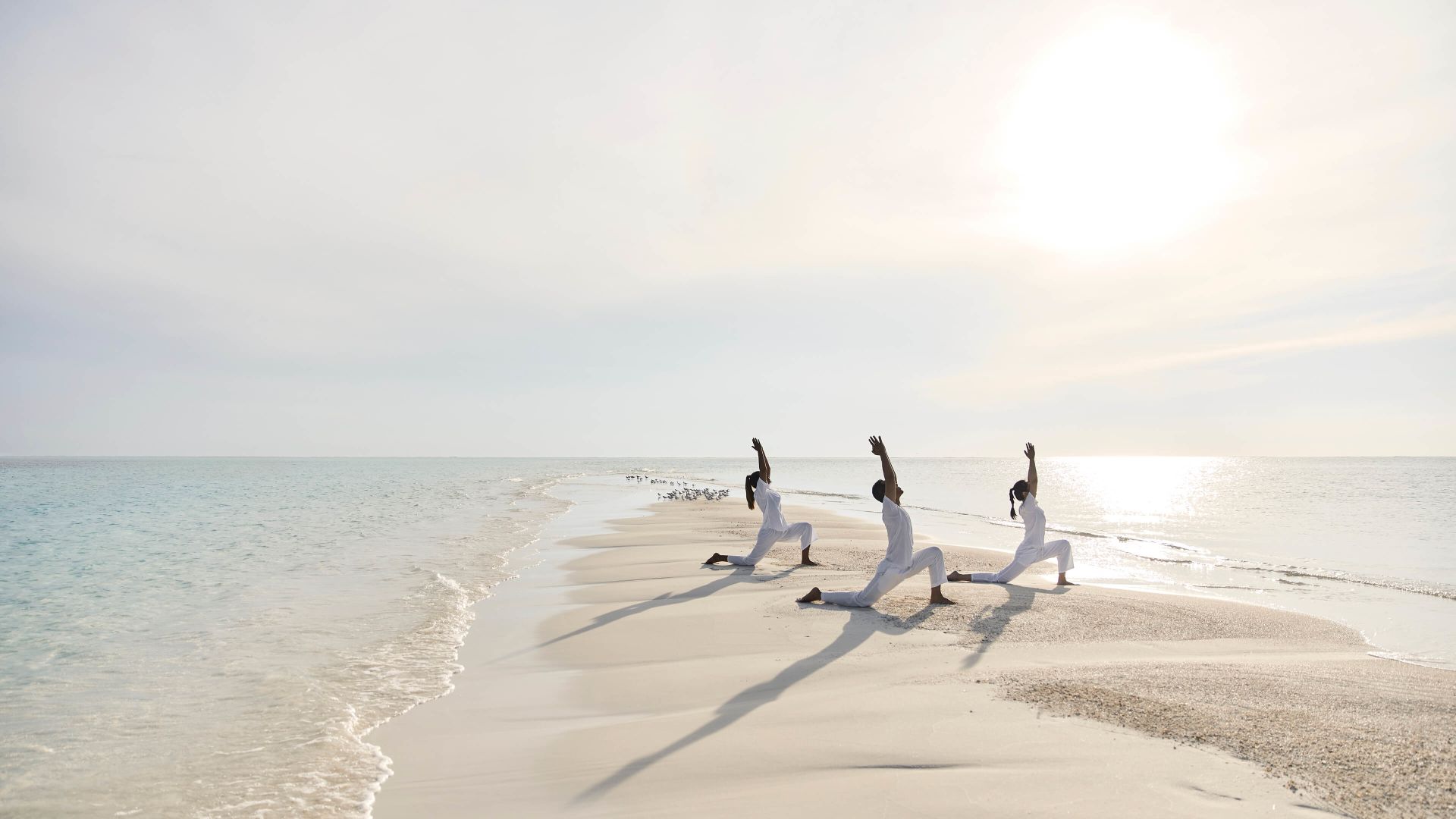 A Group Of People Jumping On A Beach