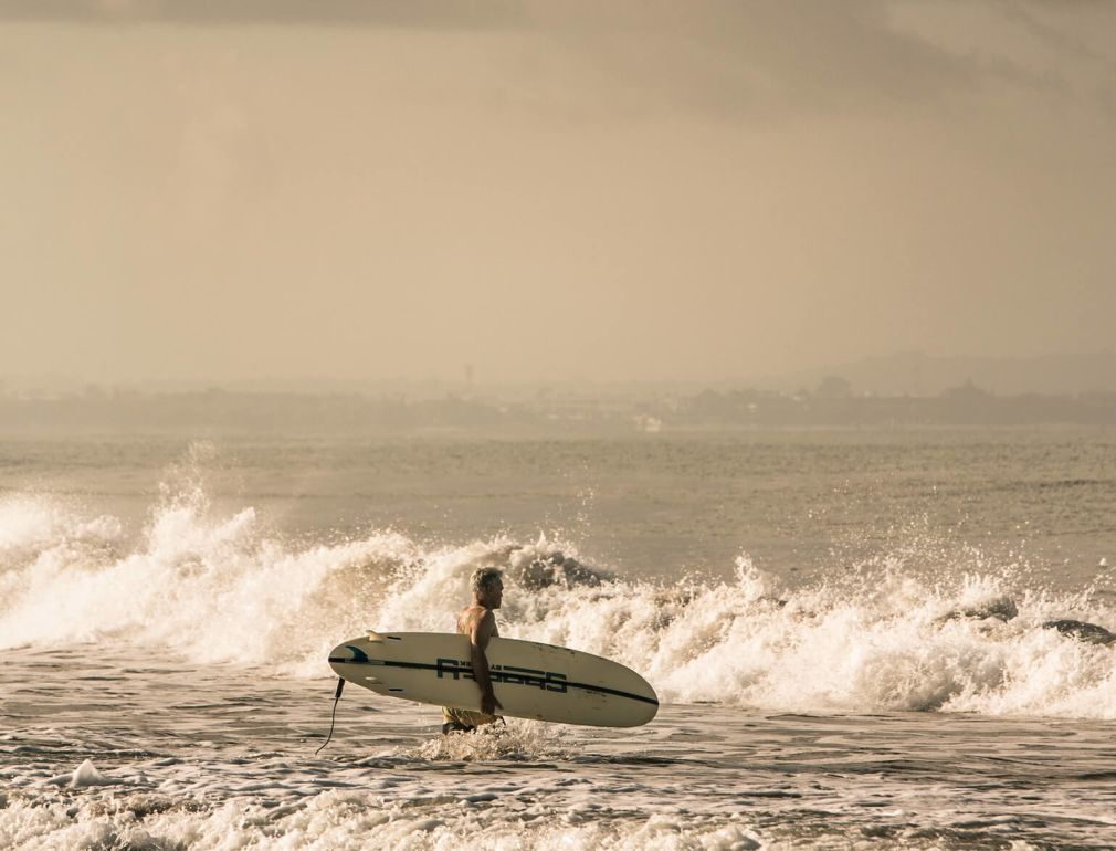 A Man Holding A Surfboard In The Ocean
