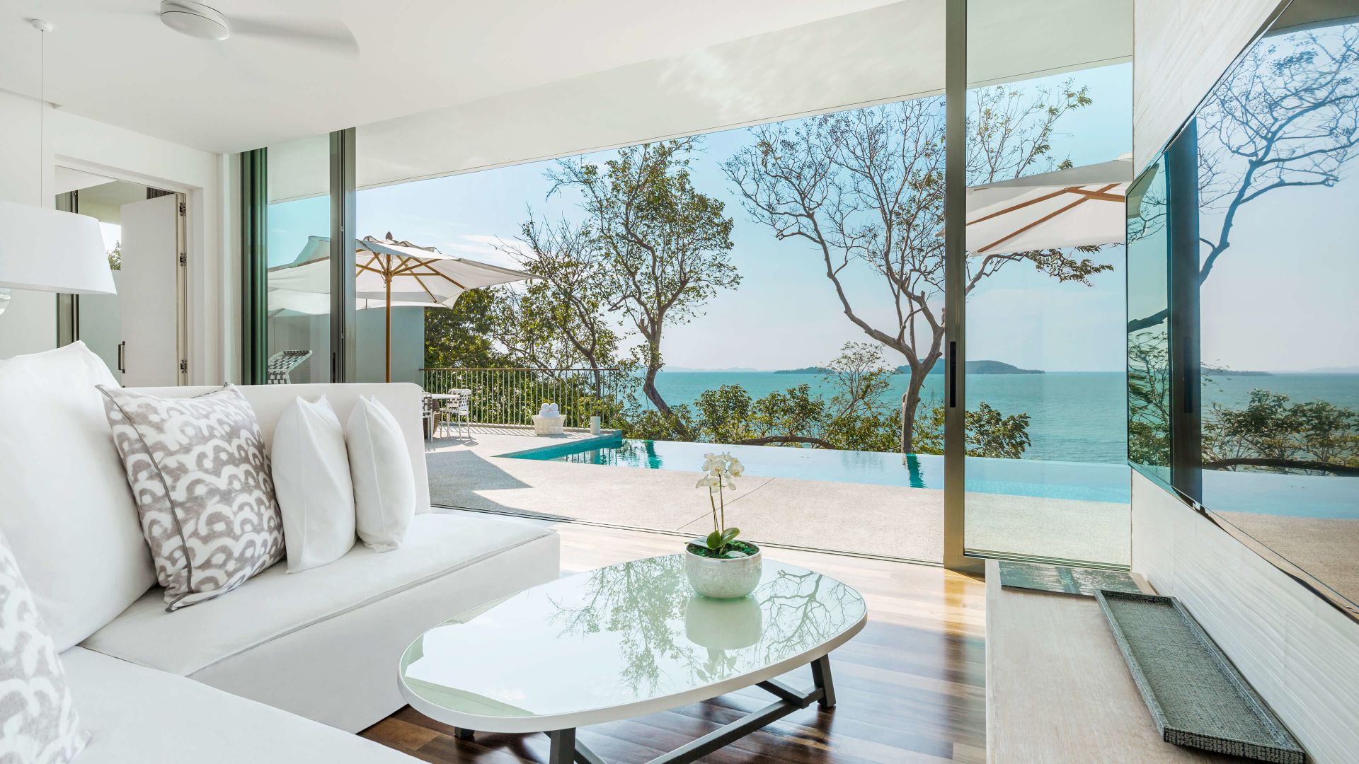 A Room With A Pool And A Large Window With Trees And A Body Of Water