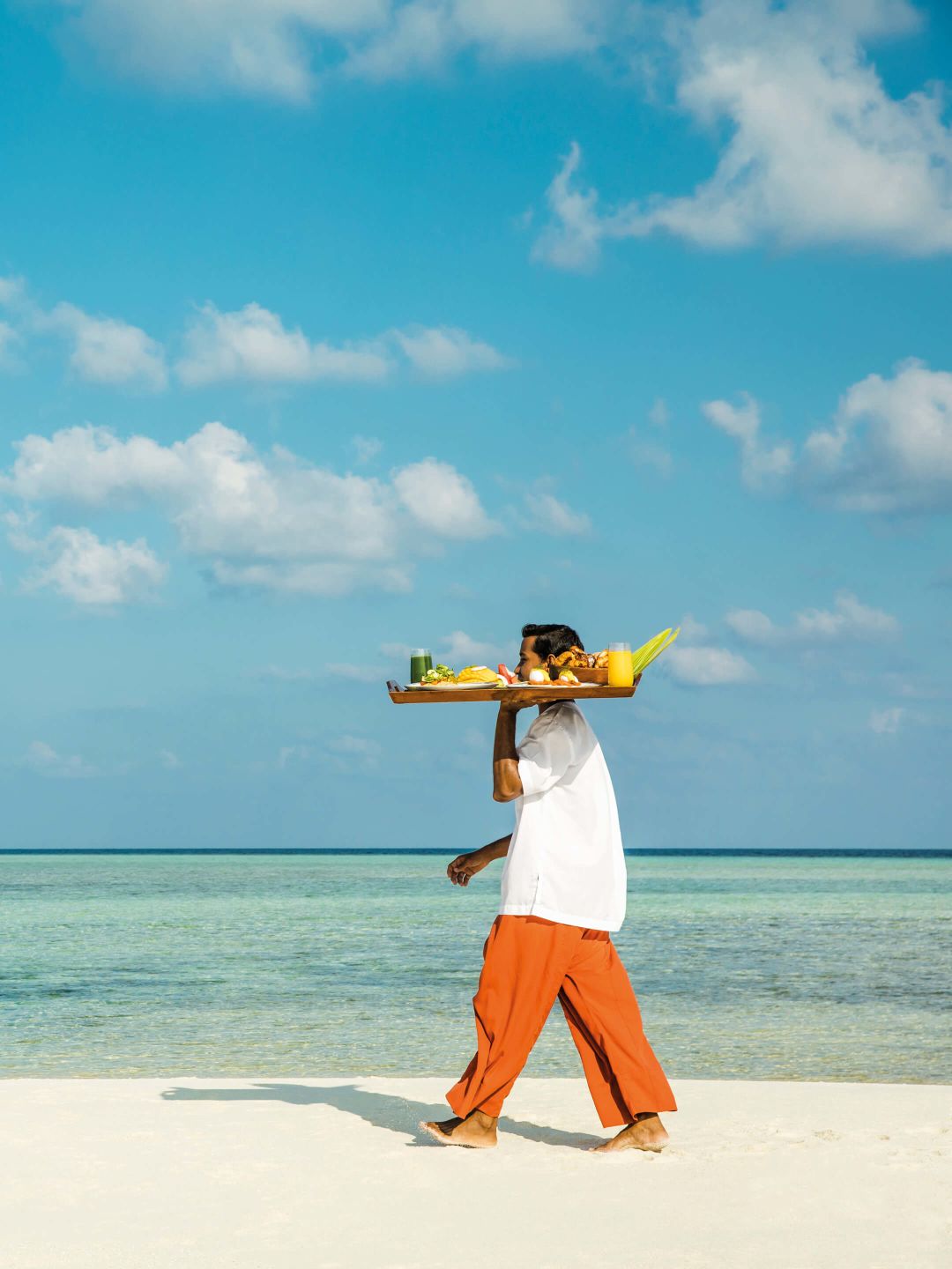 A Person Carrying A Surfboard On A Beach