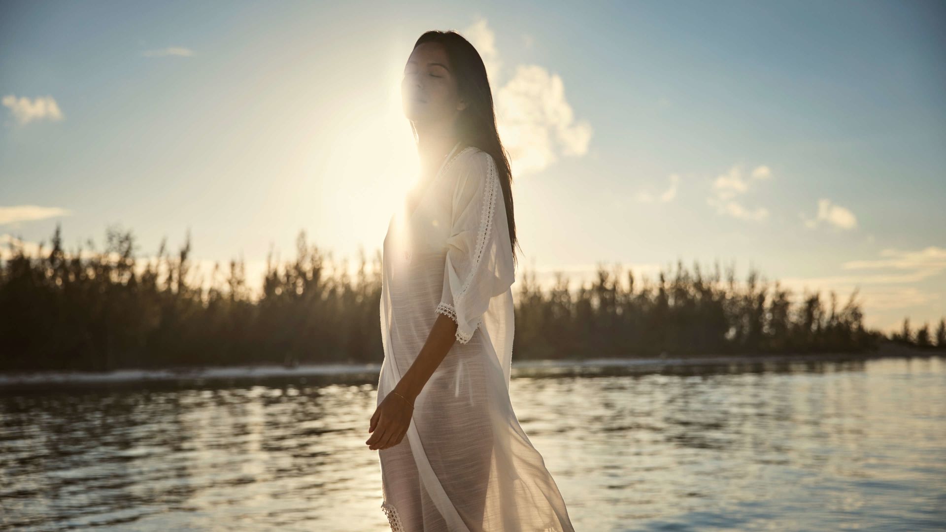 A Person In A White Dress Standing In Front Of A Lake