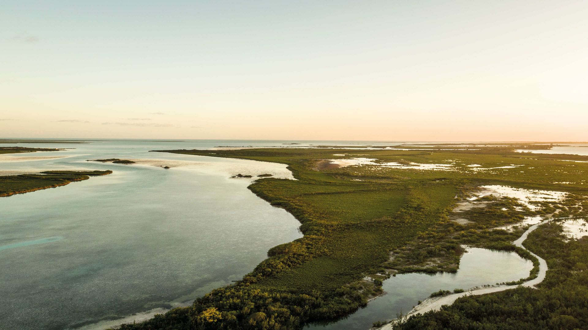A Body Of Water With Land In The Back