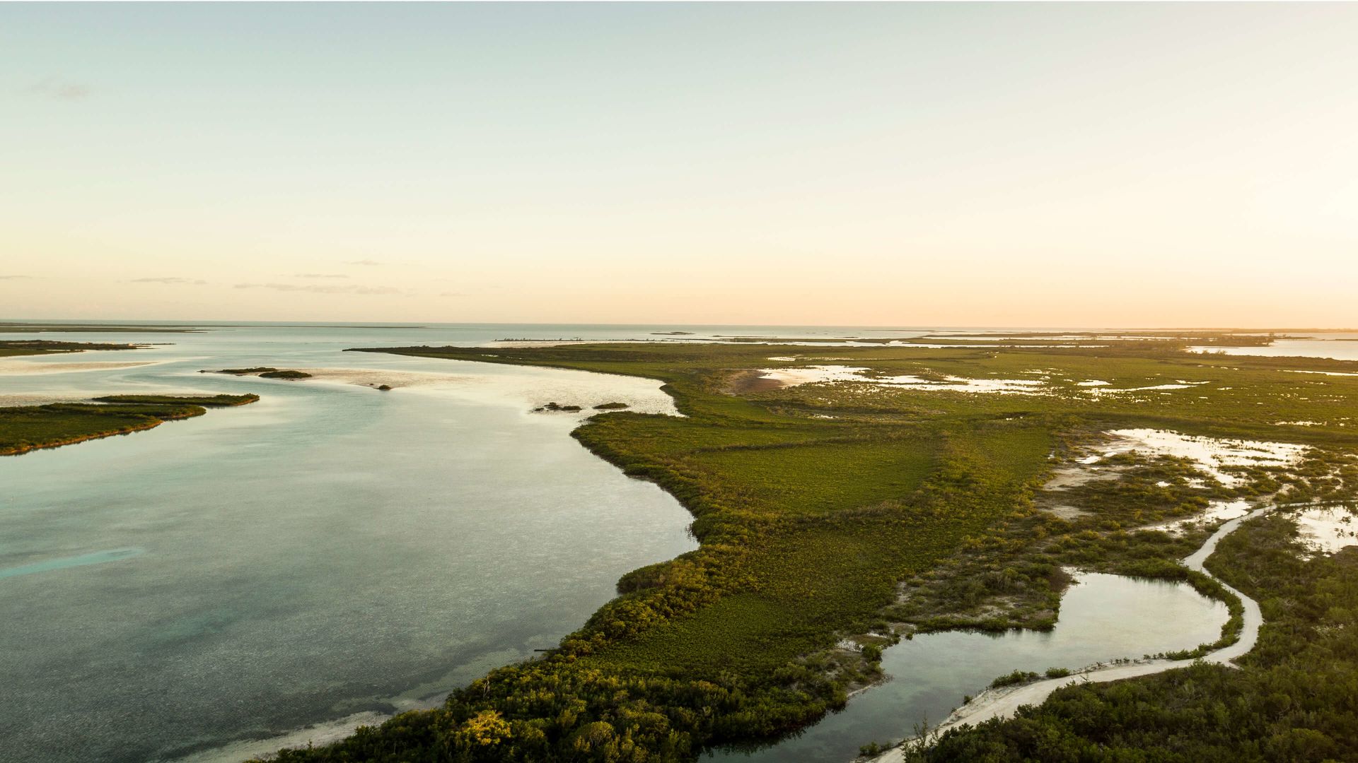 A Body Of Water With Land In The Back