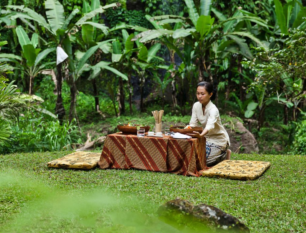 A Person Sitting At A Table In A Tropical Area