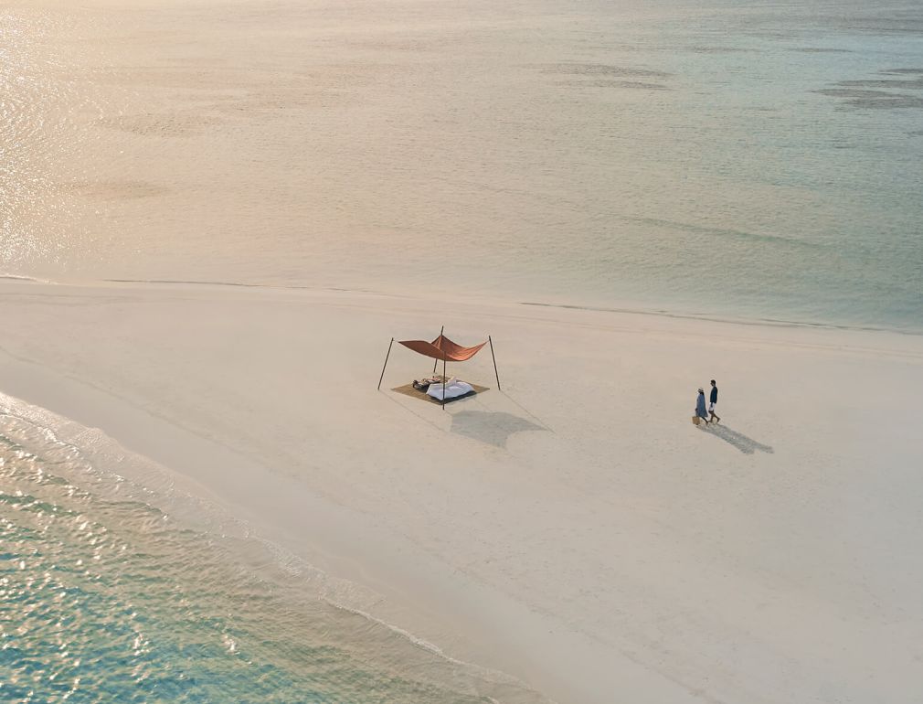 A Person On A Beach With A Chair And A Boat