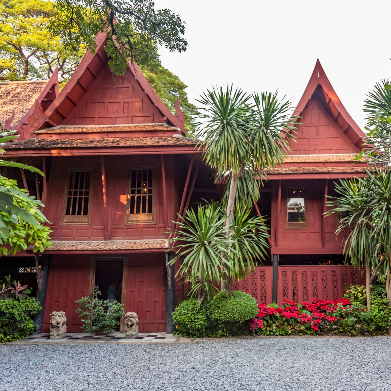 A House With Palm Trees And A Fence With Jim Thompson House In The Background