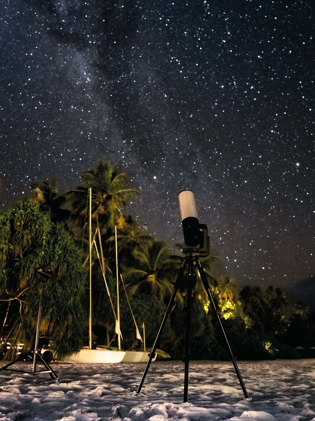 A Camera On A Tripod In The Snow With Trees And Stars In The Background