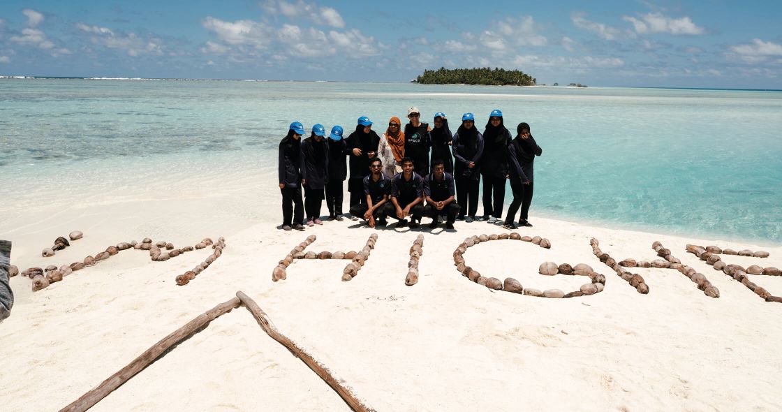 A Group Of People Posing For A Photo On A Beach
