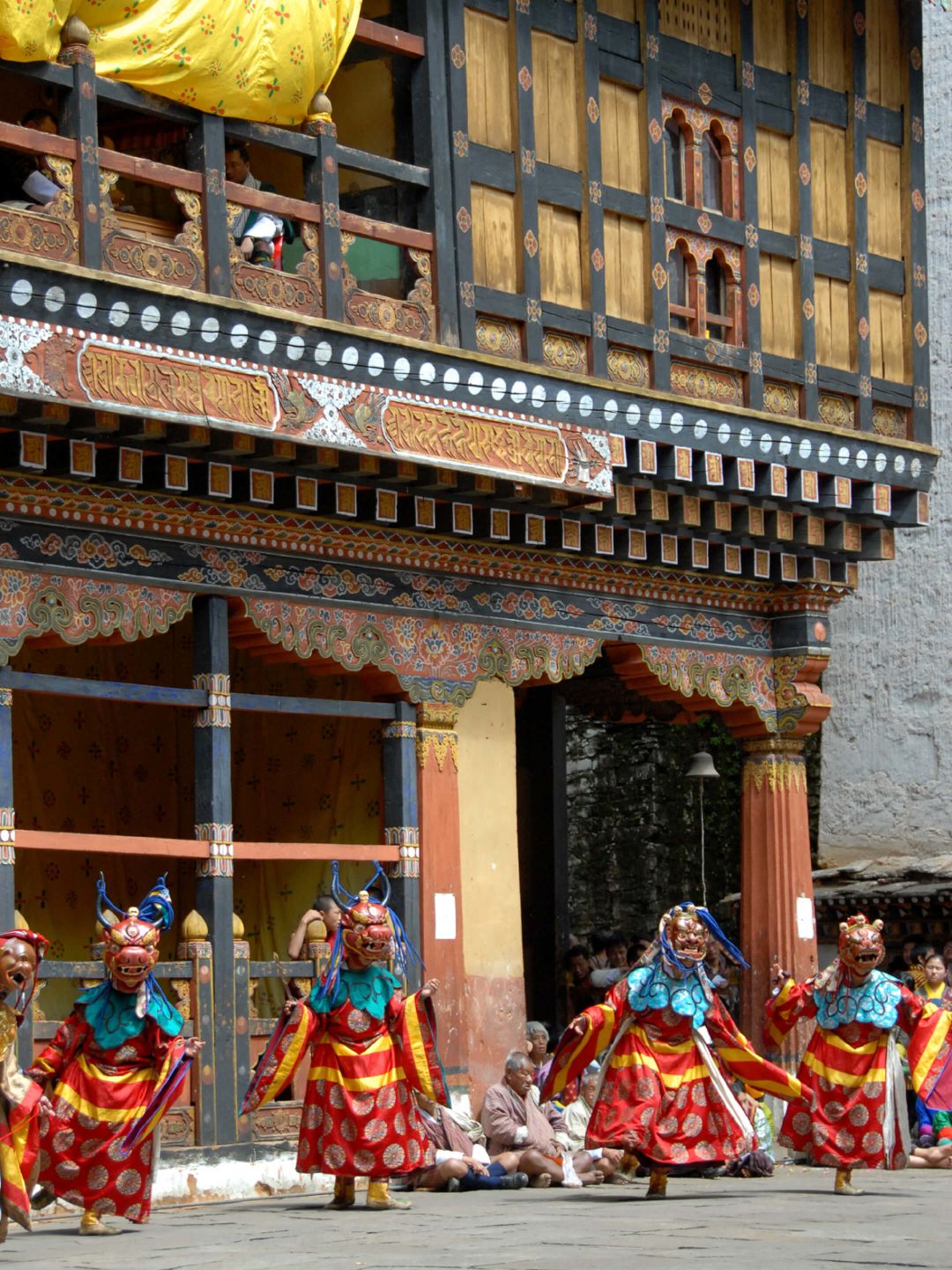 A Group Of People In Traditional Dress Dancing Outside A Building