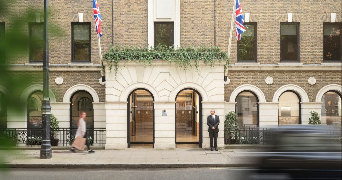 A Few Men Standing In Front Of A Building With Flags