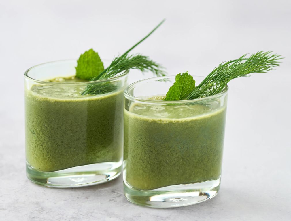 A Couple Of Glasses With Green Liquid