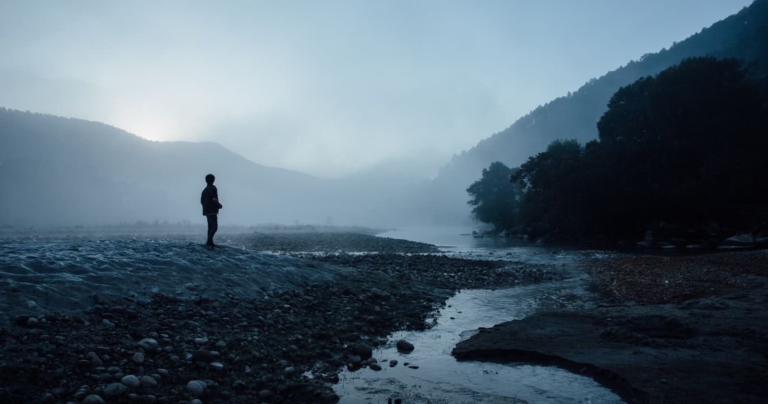 A Person Standing On A Rocky Beach