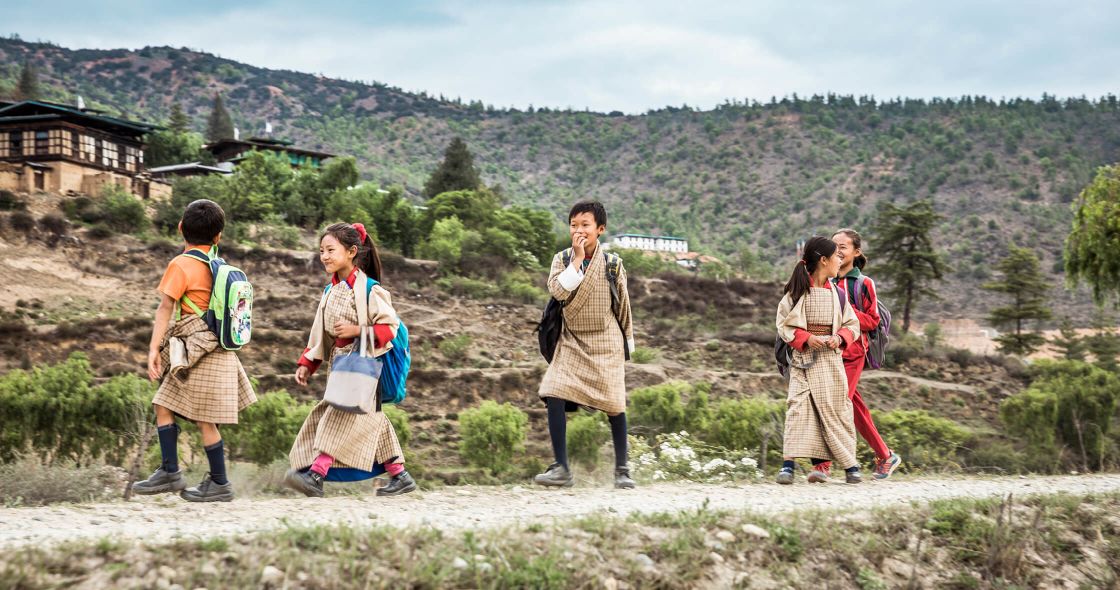 A Group Of People Standing On A Hill With Trees And Buildings In The Background