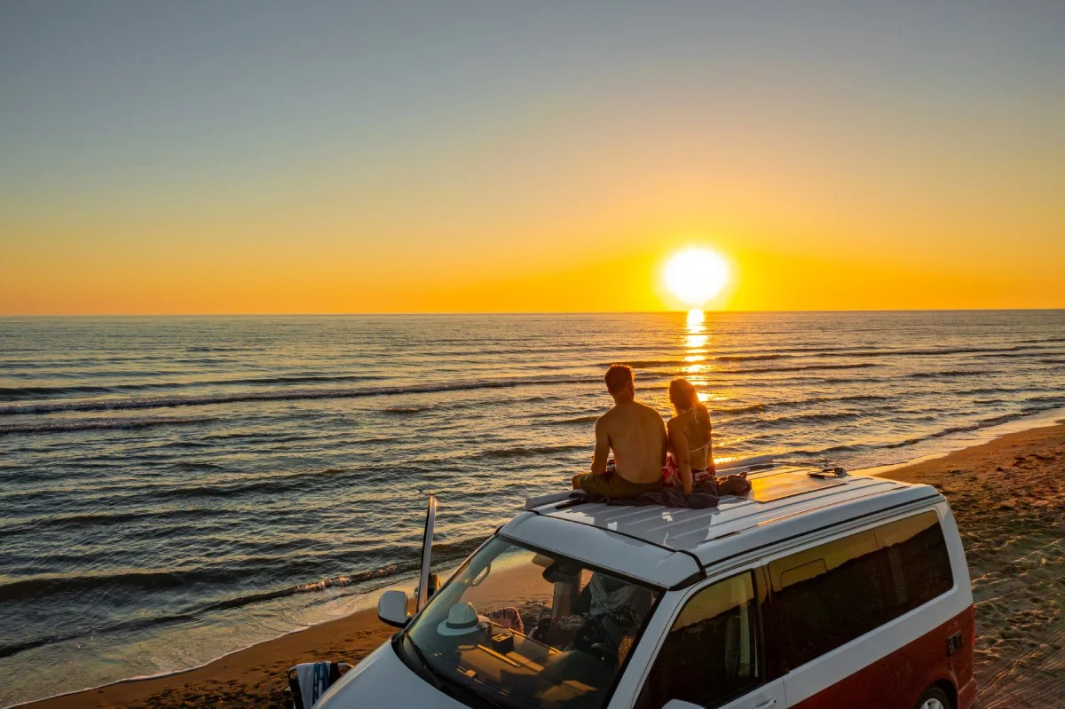 A couple admiring the sunset from the top of the campervan © iStock